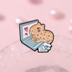 Macro detail of enamel capybara brooch using a laptop on a soft pink background