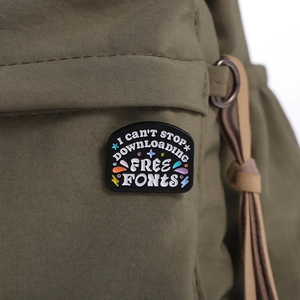 Detail of I can't stop downloading free fonts enamel pin on green nylon backpack