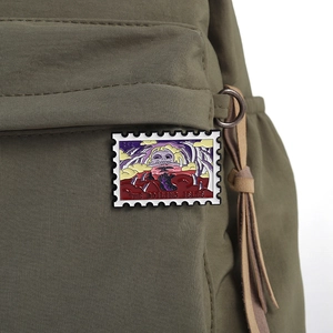 Detail of The Boiling Isles stamp enamel pin on green canvas bag texture