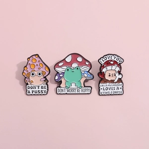 Detailed macro of funny enamel pins featuring frog and mushroom designs with humorous quotes