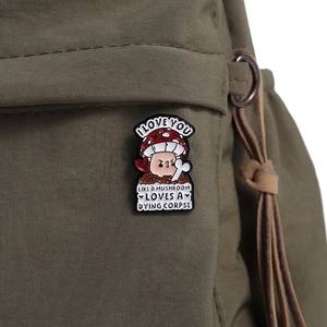 Detail of mushroom enamel pin with humorous text on a green canvas backpack