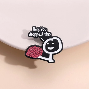 Creative enamel pin with cartoon person holding a pink brain and 'Hey You dropped this' text