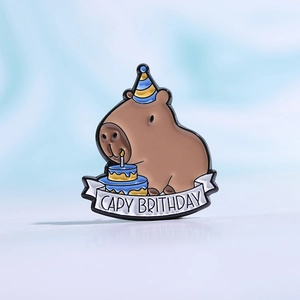 Macro shot of an enamel capybara pin featuring a party hat and a birthday cake design