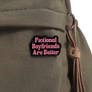 Close-up of black enamel badge with pink slogan on a green canvas backpack strap