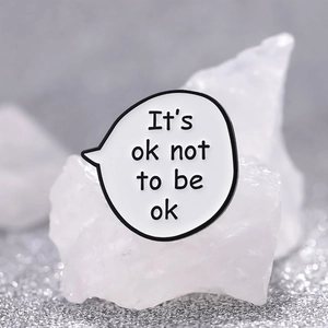 Cartoon speech bubble enamel pin featuring 'It's ok not to be ok' text on white background