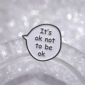 Cartoon speech bubble enamel pin with It's ok not to be ok quote on glass base