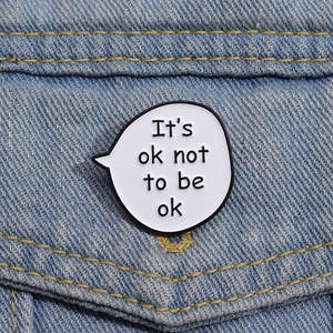 Close-up of It's Ok Not To Be Ok enamel pin on blue denim jacket pocket detail