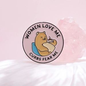 Cartoon bear enamel pin with Women Love Me text on pink crystal and white satin background