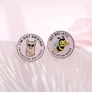 Cartoon enamel pins set with bee and alpaca illustrations on pink round badges