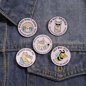 Close-up of five round cartoon animal enamel pins pinned onto a blue denim jacket sleeve