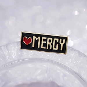 Spilla smaltata cuore pixel retro con testo MERCY e cornice dorata lucida