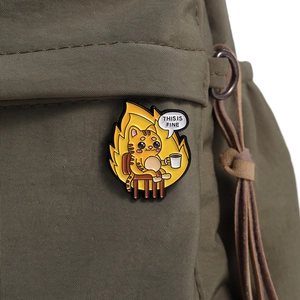 Detail of 'This Is Fine' meme cat enamel pin on olive green canvas fabric