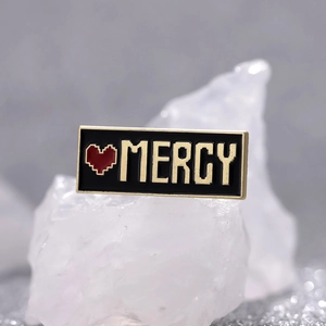 Spilla smaltata con cuore pixel e scritta MERCY su base di cristallo bianco