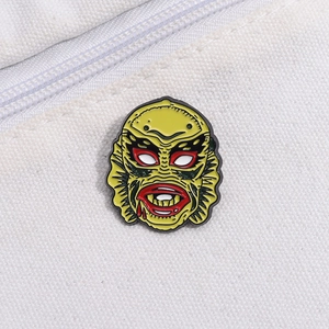 Macro shot of green monster enamel pin on white canvas background with zipper detail