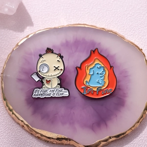 Voodoo doll and internet meme dog enamel pins on a decorative purple display plate