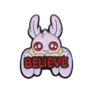 Cartoon white monster enamel pin with red eyes holding a BELIEVE banner on white background