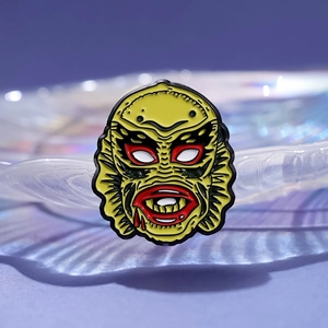 Unique yellow creature from the black lagoon enamel pin on a purple background