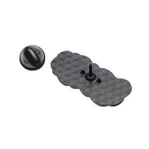 Macro detail of matte black metal brooch back with grid texture and rubber pin clutch