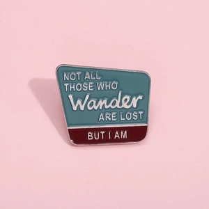 Broche en émail avec message Not All Those Who Wander Are Lost sur fond rose pastel