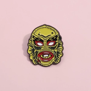 Cartoon monster head enamel pin featuring green scales and scary fish features for clothing