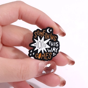 Cartoon enamel pin with Something Wicked This Way Comes text and moon star design