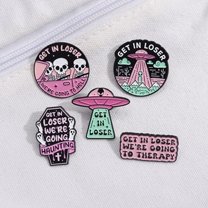 Five purple cartoon alien skull enamel pins set displayed on a white canvas bag
