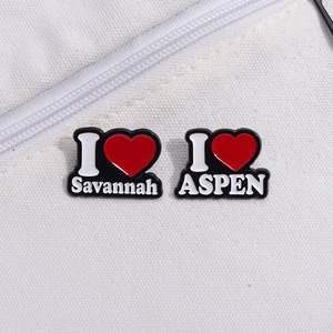 Zwei Emaille-Anstecknadeln mit Savannah- und Aspen-Schriftzug und roten Herzdetails