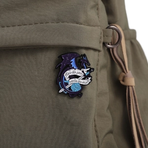 Macro detail of dragon and d20 dice enamel pin on green canvas bag