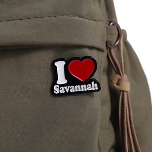 Vue macro du pin's émaillé I Love Savannah sur un sac en toile verte montrant les détails