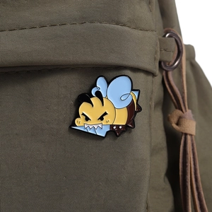 Detailed view of creative angry bee enamel pin attached to a green canvas backpack
