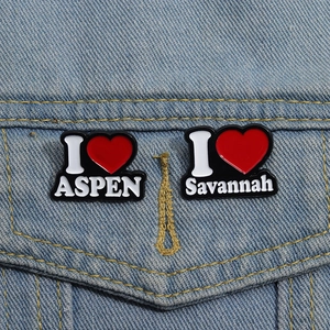 Detail von I Love ASPEN und Savannah Emaille-Anstecknadeln auf blauem Denim-Stoff