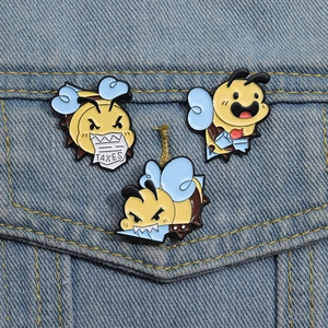Set of three cute cartoon bee enamel pins on denim jacket featuring a bee biting taxes sign