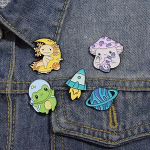 Detail of cute cartoon enamel pins with astronaut frog and axolotl on denim jacket