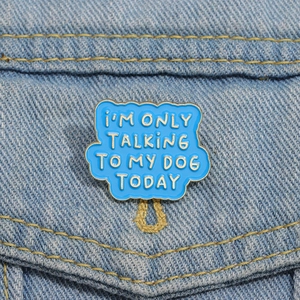Détail d'un badge en émail bleu avec slogan pour chien épinglé sur une veste en jean