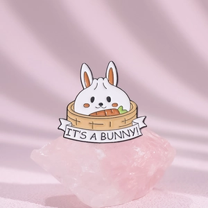 Cartoon enamel bunny brooch pin in yellow steamer basket with carrot and banner text