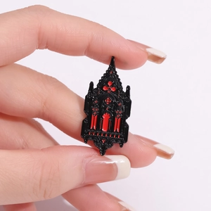 Gothic castle cathedral brooch in black and red enamel finish held by fingers