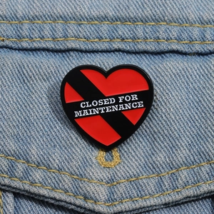 Macro di spilla a cuore in smalto rosso e nero con scritta su una giacca di jeans