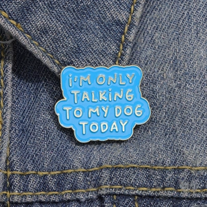 Enamel pin with I'M ONLY TALKING TO MY DOG TODAY text on blue denim fabric
