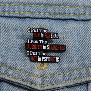 Black enamel inspirational quote brooch pinned on a blue denim jacket pocket accessory