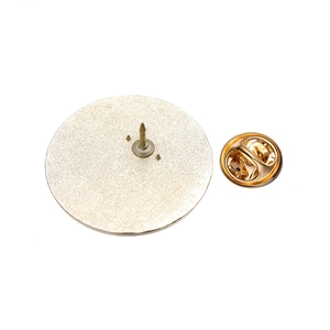Détail du dos d'une broche ronde en métal doré sablé avec son fermoir papillon inclus