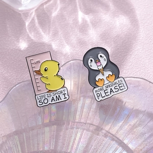 Cute cartoon animal enamel pins featuring a yellow duck and penguin with funny quotes