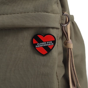 Gros plan d'un pin's en forme de cœur rouge avec texte sur un sac à dos en nylon vert