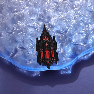 Gothic architectural brooch with red enamel and black metal frame on water ripple texture