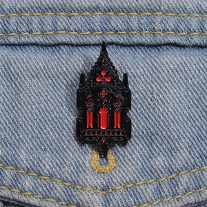 Gothic cathedral window brooch with black and red enamel on blue denim background