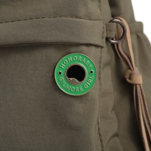 Gros plan sur le pin's Honorary Gilmore Girl en émail fixé sur un sac en nylon vert