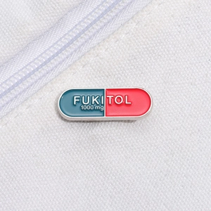 Funny Fukitol capsule enamel pin with red and teal colors on white canvas background