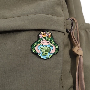 Close-up of a Mother Earth Day enamel pin attached to a green canvas backpack