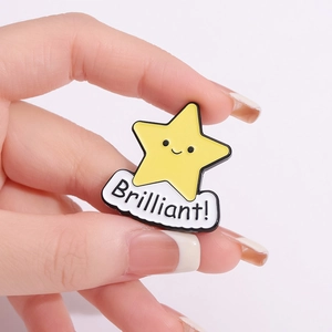 Cute yellow star enamel pin with Brilliant text and white cloud, hand-held closeup