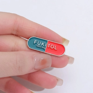 Funny pill shaped enamel pin with FUKITOL text and red blue contrast design