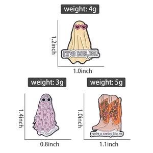 Detailed view of three enamel pins including ghost figures and floral cowboy boots